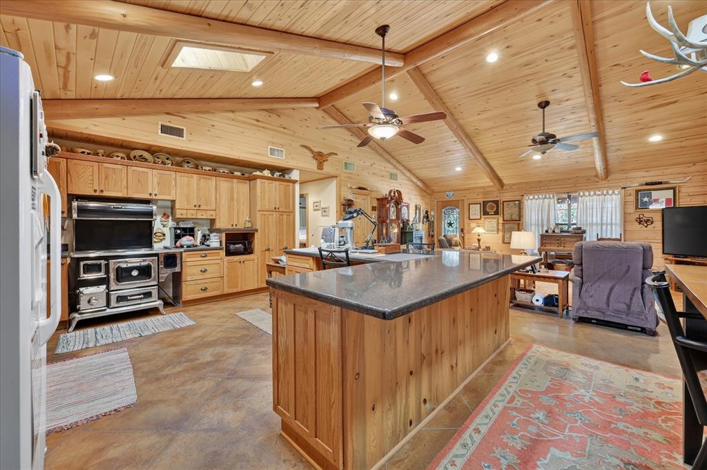 1623 3 Skillet Road Springtown, TX 76082 - Photo 19 of 40 Expansive open-concept room featuring vaulted wood-paneled ceilings, exposed wood beams, a skylight, recessed lighting, and ceiling fans
