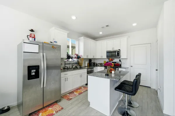 a kitchen with stainless steel appliances kitchen island granite countertop a refrigerator and a stove top oven