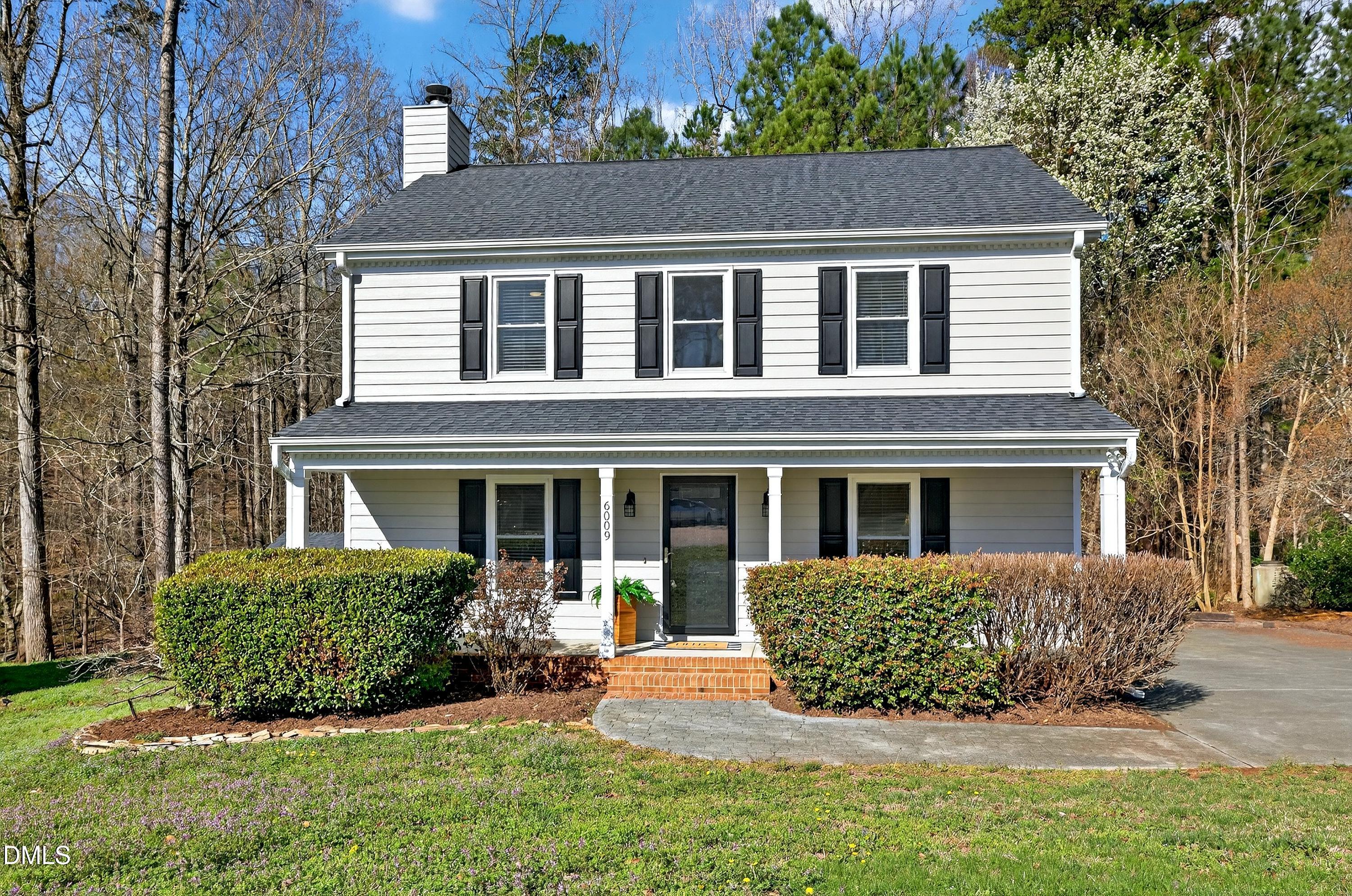 a view of a house with a yard plants and large tree