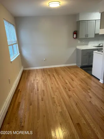 a view of kitchen and empty room with wooden floor