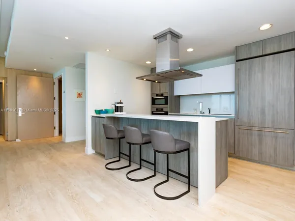 a kitchen with stainless steel appliances kitchen island a table chairs in it and wooden floors