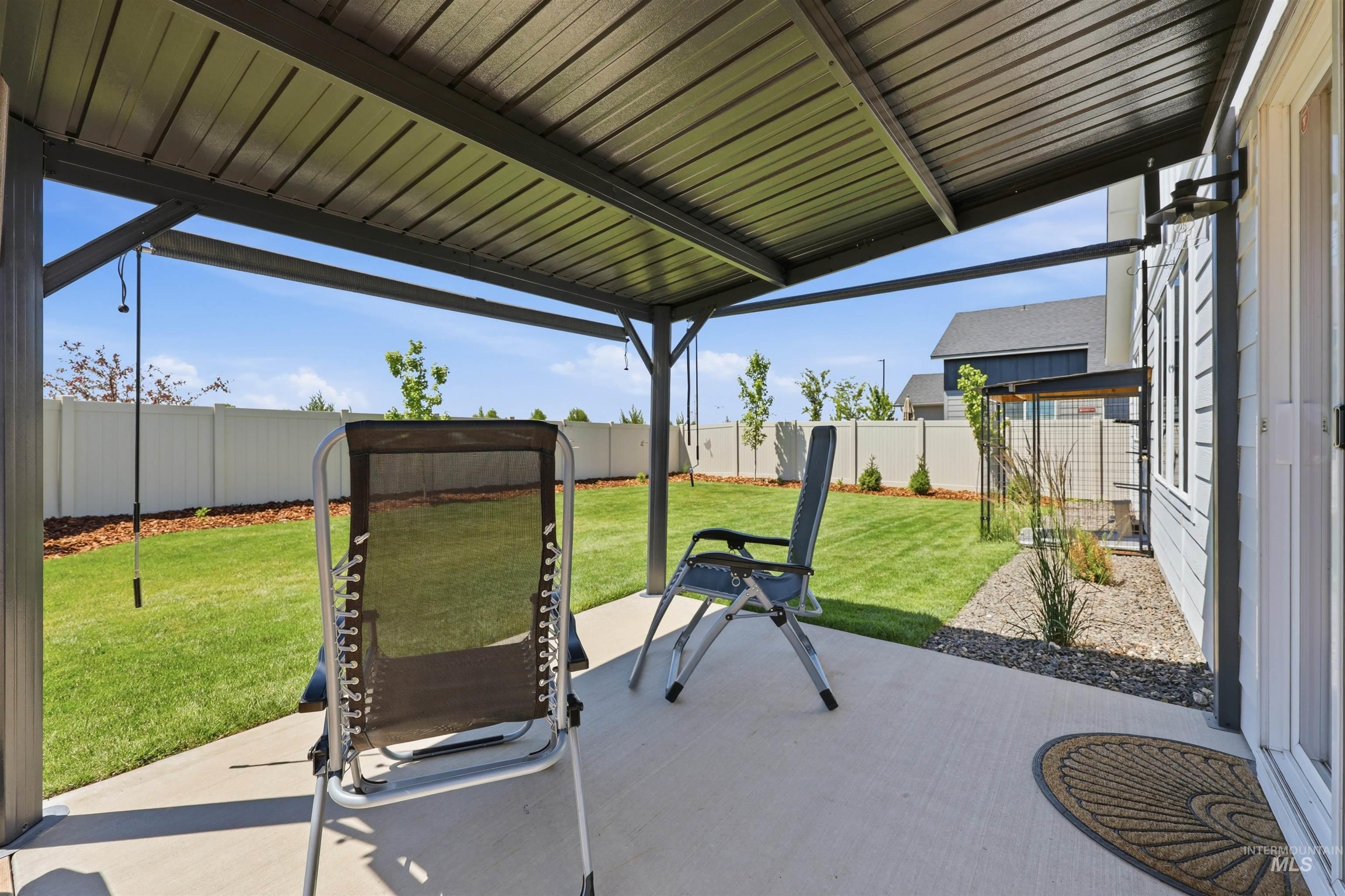 3811 West Maypearl Street Meridian, ID 83642 - Photo 30 of 39 Expansive concrete patio beneath a metal-roofed pergola, offering direct access to a manicured lawn