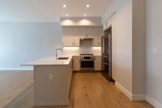 a kitchen with a sink a counter top space stainless steel appliances and cabinets