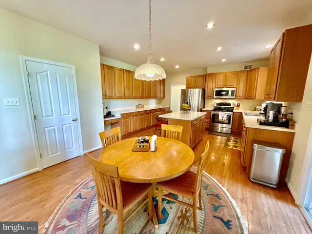 a kitchen with stainless steel appliances granite countertop a refrigerator a stove top oven a sink and dishwasher with wooden floor