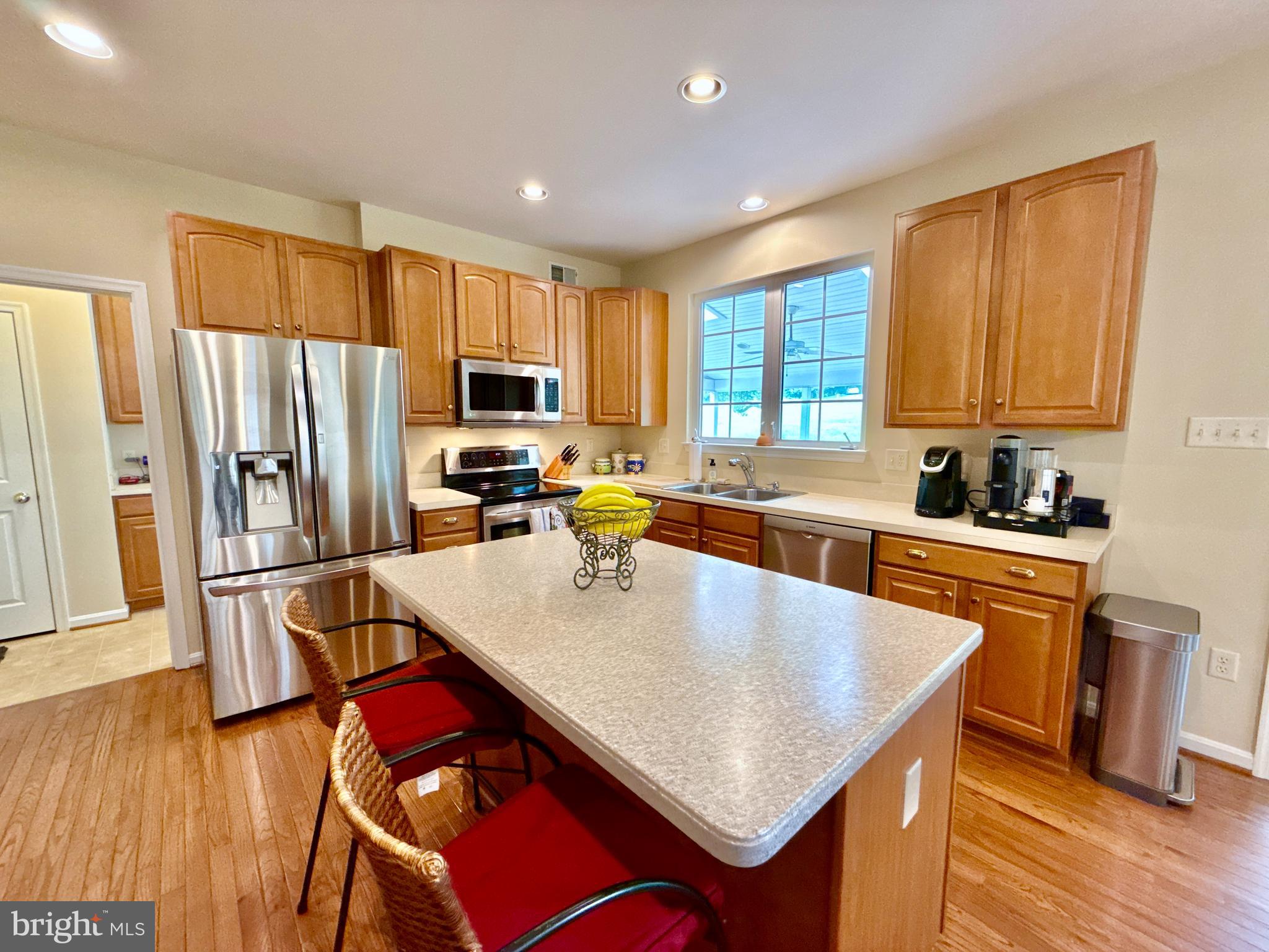 14100 Twisting Lane Dayton, MD 21036 - Photo 21 of 63 a kitchen with stainless steel appliances granite countertop a refrigerator a stove top oven a sink dishwasher and white cabinets with wooden floor