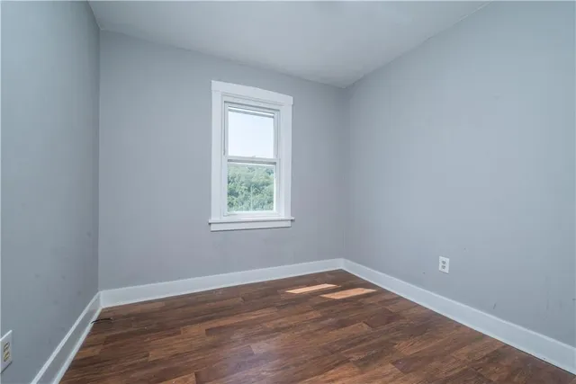 an empty room with wooden floor and a window