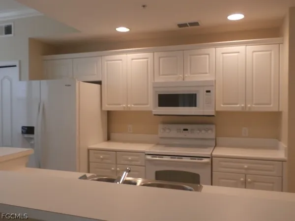 a kitchen with granite countertop white cabinets and refrigerator