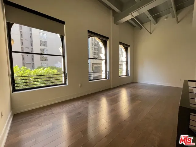 a view of an empty room with a window and wooden floor