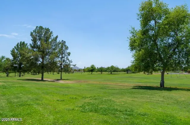 a view of grassy field with benches and trees around