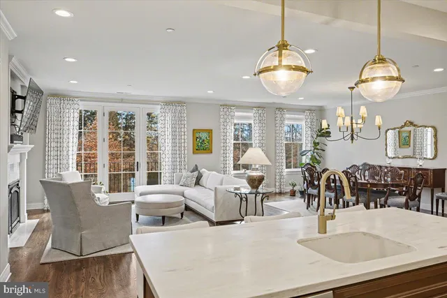 a living room with couches chandelier and a dining table with wooden floor