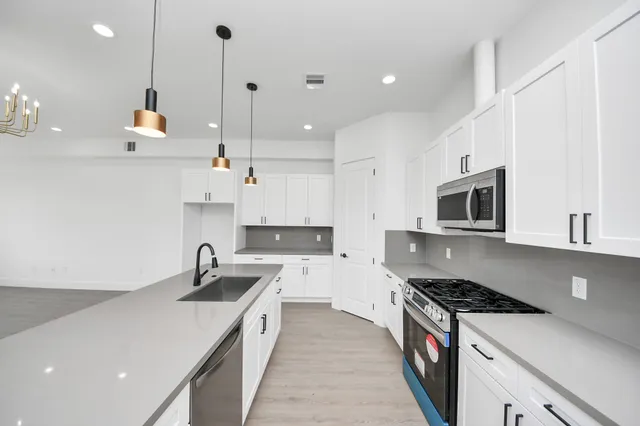 a kitchen with a sink chandelier and wooden floor
