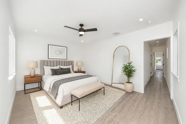 a large kitchen with stainless steel appliances kitchen island granite countertop a stove a sink a refrigerator and white cabinets with wooden floor