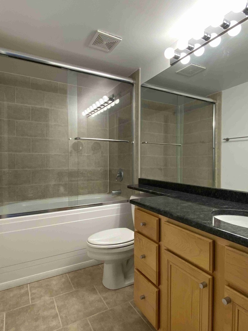 500 South Clinton Street, Unit 1017 Chicago, IL 60607 - Photo 10 of 11 a bathroom with a granite countertop sink a toilet and bathtub