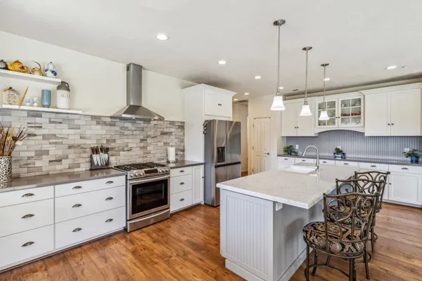 a kitchen with stainless steel appliances kitchen island granite countertop a sink a stove and a refrigerator