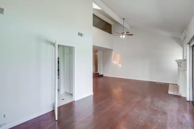 a view of an entryway with wooden floor leading to a furnished livingroom and windows