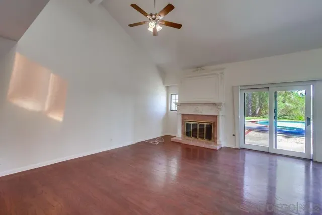 a view of an empty room with wooden floor and a floor to ceiling window