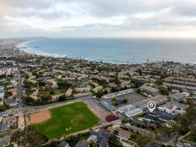 an aerial view of a city with lots of residential buildings and ocean view in back