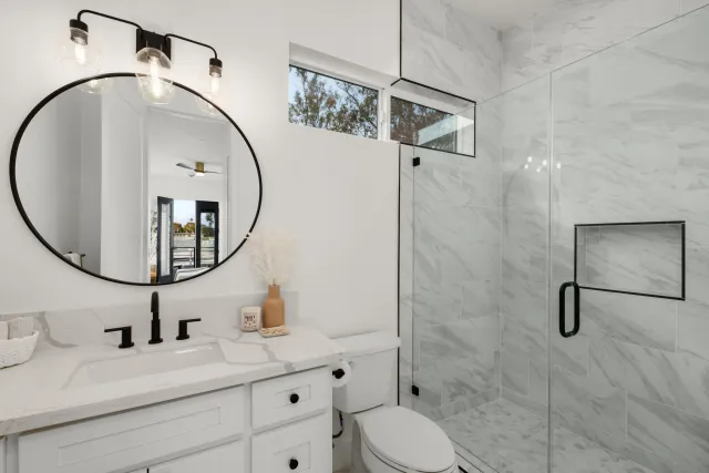 a bathroom with a toilet sink vanity granite and shower