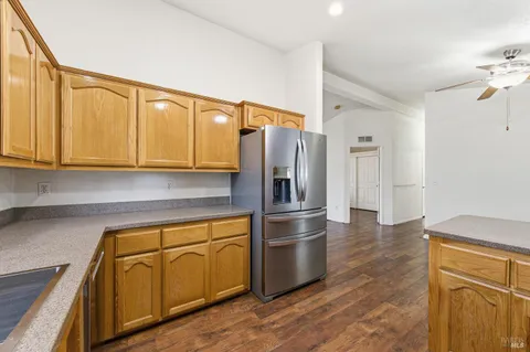 a kitchen with stainless steel appliances granite countertop a refrigerator a sink dishwasher and wooden cabinets with wooden floor
