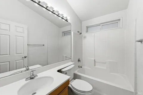 a bathroom with a bathtub shower sink vanity mirror and toilet