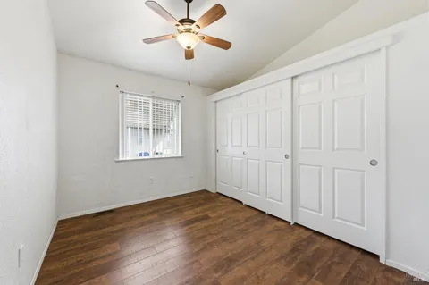 an empty room with wooden floor chandelier fan and windows