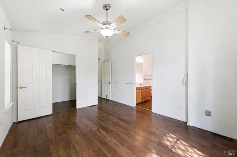 an empty room with wooden floor and a ceiling fan
