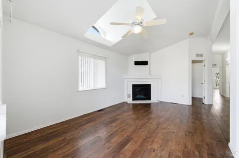 an empty room with wooden floor fireplace and windows