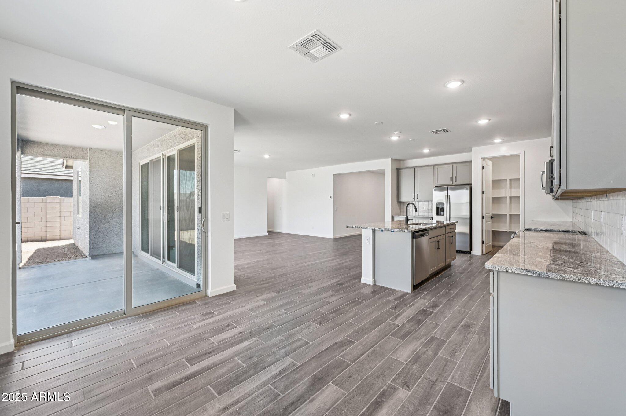 15794 West Cheryl Drive Waddell, AZ 85355 - Photo 6 of 53 a large kitchen with a center island wooden floor stainless steel appliances and windows