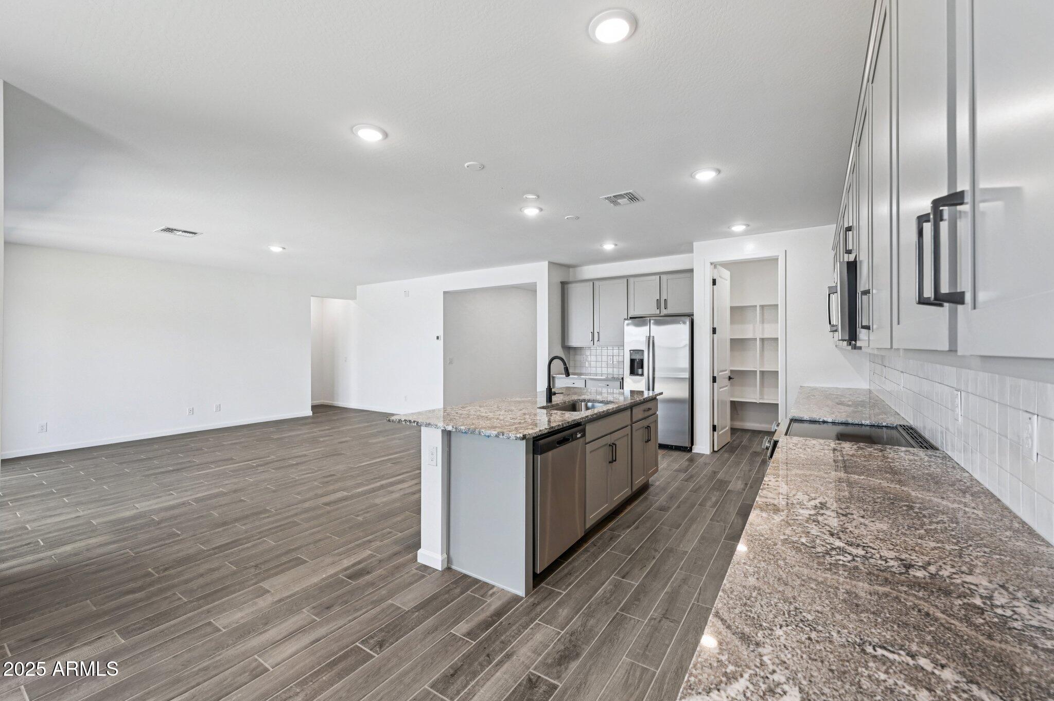 15794 West Cheryl Drive Waddell, AZ 85355 - Photo 7 of 53 a kitchen with stainless steel appliances granite countertop a stove and a sink