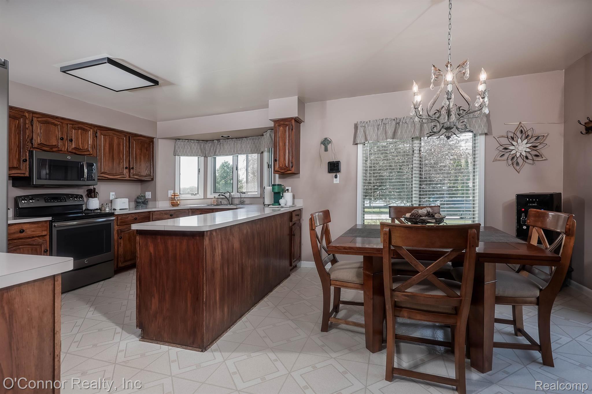7978 Frith Road Columbus, MI 48063 - Photo 9 of 56 Kitchen featuring stainless steel appliances, light countertops, a peninsula, light floors, and suspended lighting