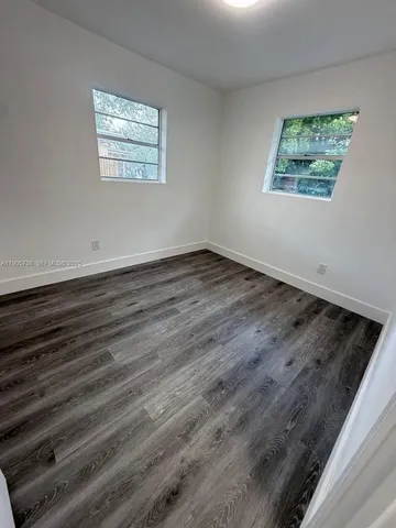 an empty room with wooden floor and window