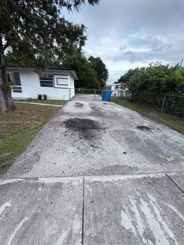 a view of a dry yard with a house and a forest