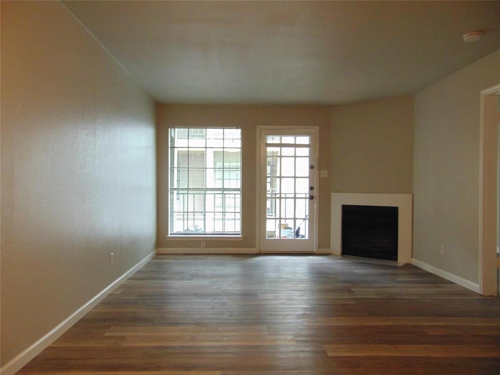 6108 Abrams Road, Unit 311 Dallas, TX 75231 - Photo 11 of 14 an empty room with wooden floor and fireplace