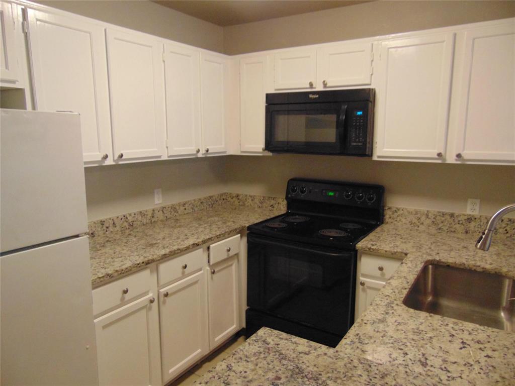 6108 Abrams Road, Unit 311 Dallas, TX 75231 - Photo 9 of 14 a kitchen with granite countertop white cabinets and black appliances