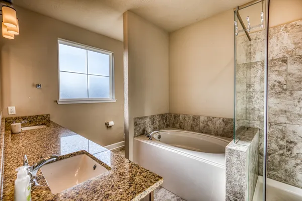 a bathroom with a granite countertop tub a sink and a window