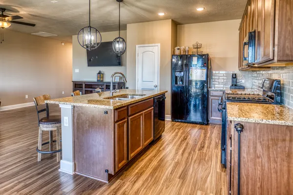 a kitchen with stainless steel appliances granite countertop a sink a stove and a refrigerator