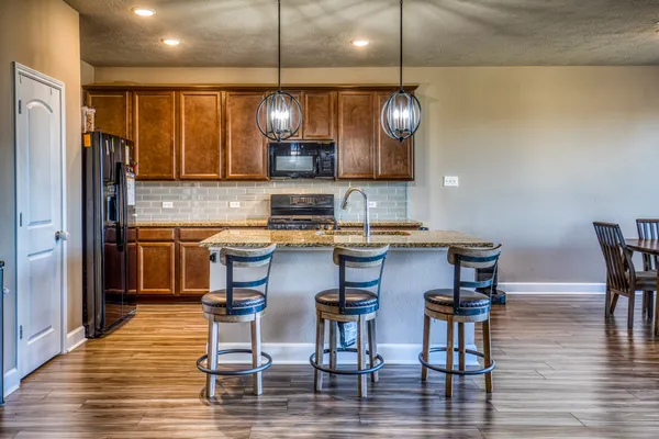 a kitchen with stainless steel appliances granite countertop a kitchen island a stove a table and chairs