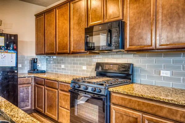 a kitchen with granite countertop a stove a sink and a microwave