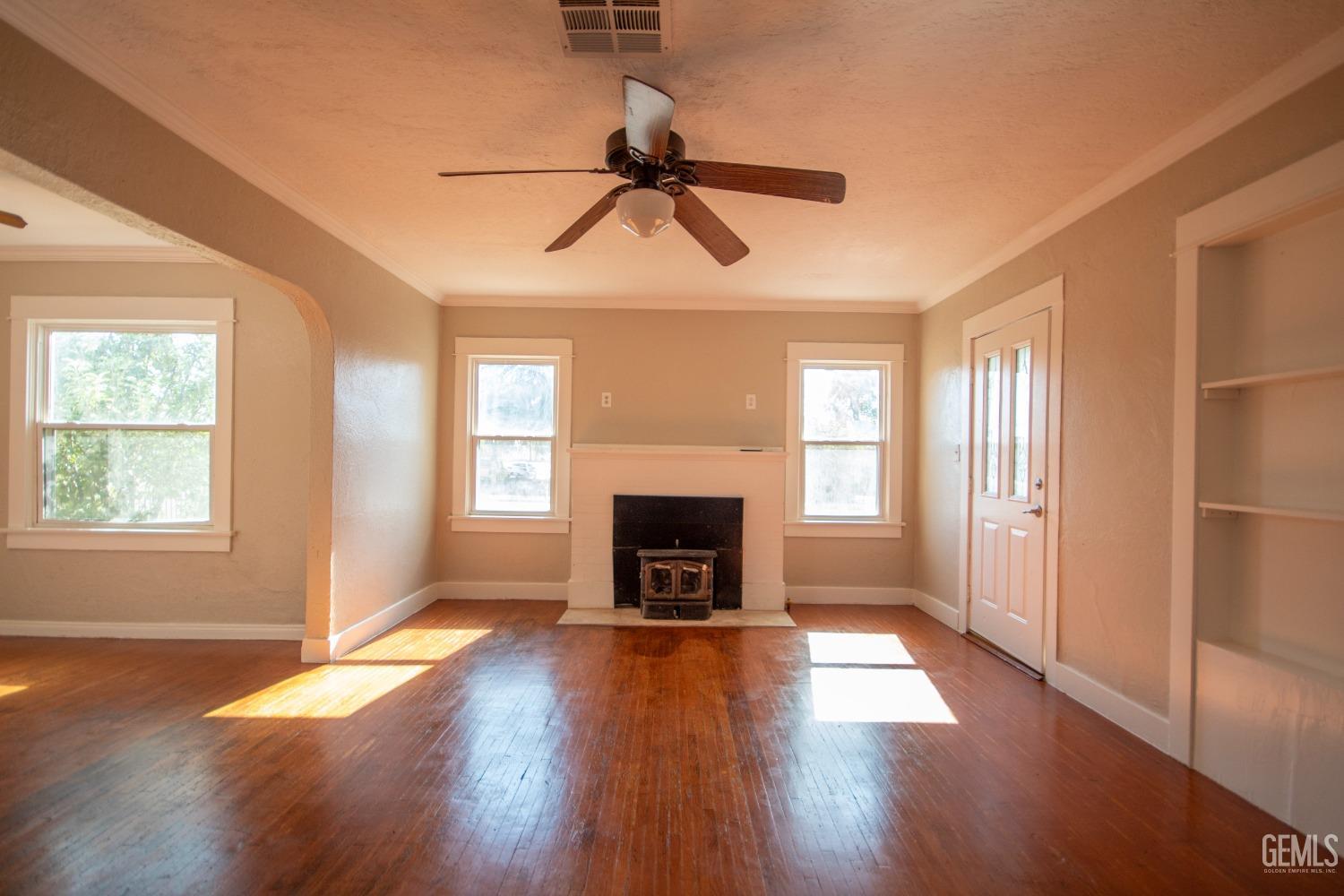 Undisclosed Address Bakersfield, CA 93305 - Photo 4 of 20 an empty room with windows fireplace and wooden floor