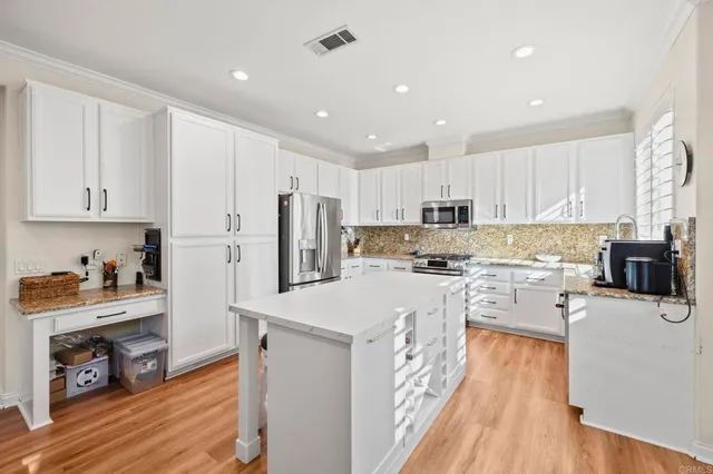 a kitchen with refrigerator a stove a sink and wooden floor