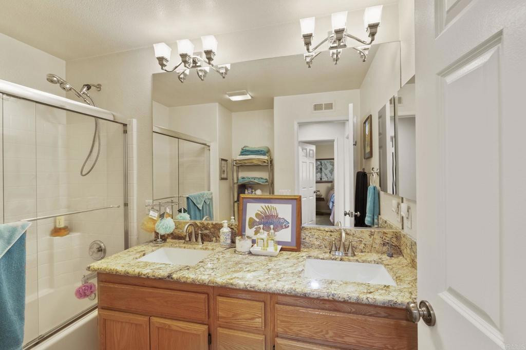 3033 Rancho La Presa Carlsbad, CA 92009 - Photo 18 of 46 a bathroom with a granite countertop sink mirror and a shower