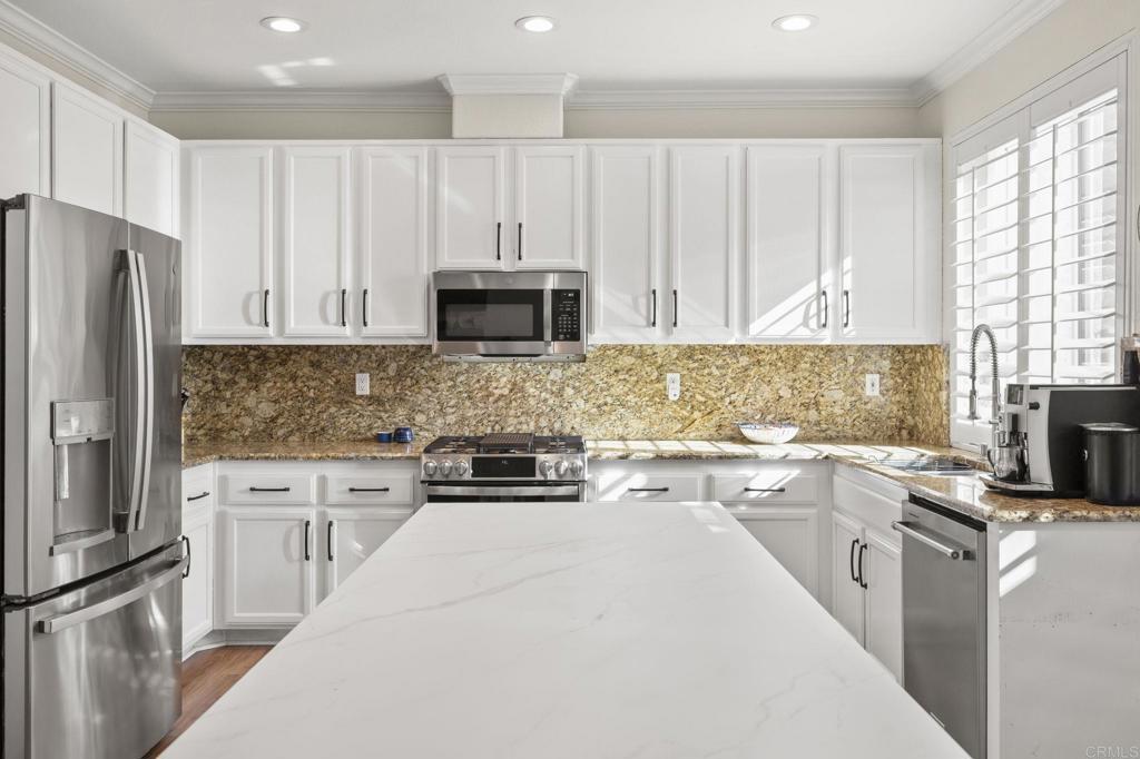 3033 Rancho La Presa Carlsbad, CA 92009 - Photo 2 of 46 a kitchen with kitchen island white cabinets stainless steel appliances a sink and a window