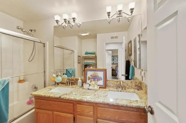 a bathroom with a granite countertop sink mirror and a shower