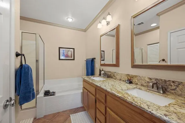 a bathroom with a granite countertop double vanity sink and mirror