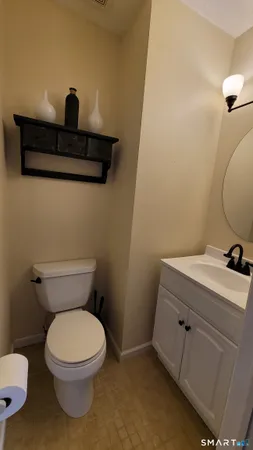a bathroom with a toilet a sink and wooden floor