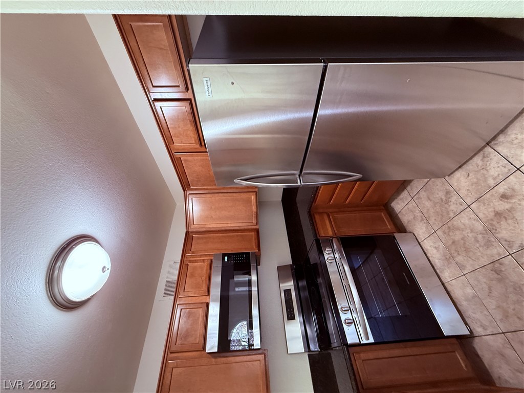 9325 West Desert Inn Road, Unit 260 Las Vegas, NV 89117 - Photo 12 of 42 A contemporary kitchen offers sleek stainless steel appliances paired with warm wood cabinetry and durable tile flooring.