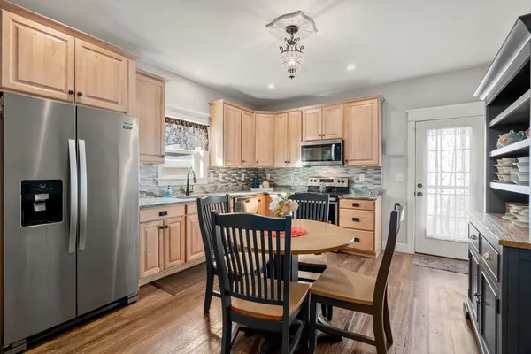 a kitchen with stainless steel appliances granite countertop a refrigerator a stove a sink dishwasher a dining table and chairs with wooden floor