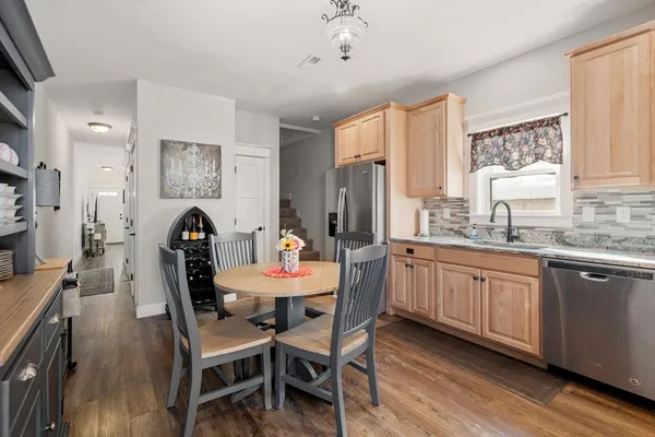 a kitchen with stainless steel appliances kitchen island granite countertop a dining table chairs and a refrigerator