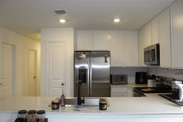 a kitchen with stainless steel appliances kitchen island granite countertop a refrigerator a stove and a sink