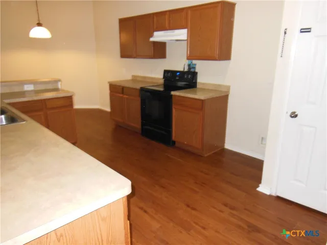 a kitchen with stainless steel appliances wooden cabinets and wooden floor